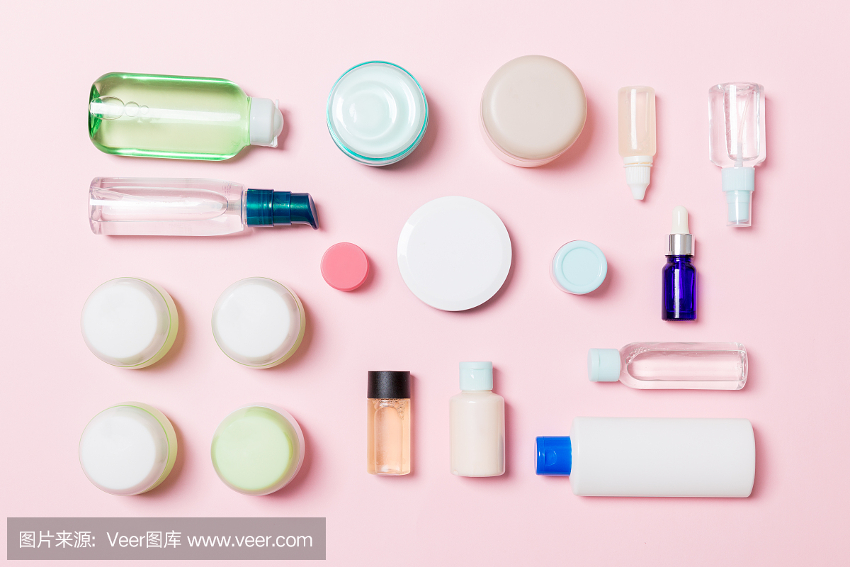 组塑料美体瓶平铺构图与化妆品在粉红色的背景空为您设计。一套白色化妆品容器,顶视图与复制空间
